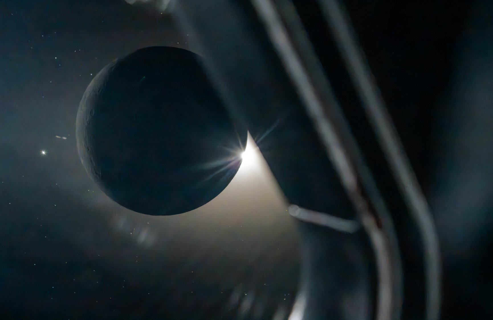 The Moon, backlit by the Sun, seen past spacecraft structure. Photograph by Andrew McCarthy.