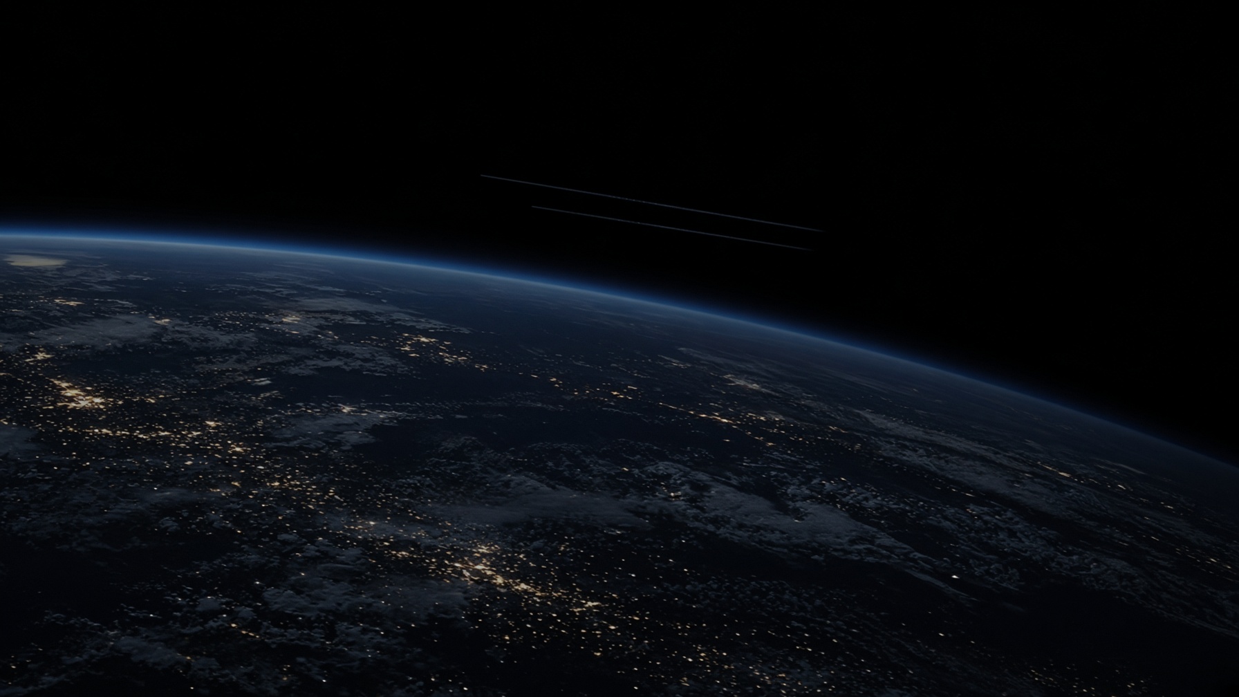 Night-side Earth from orbit with two faint satellite trails far apart.