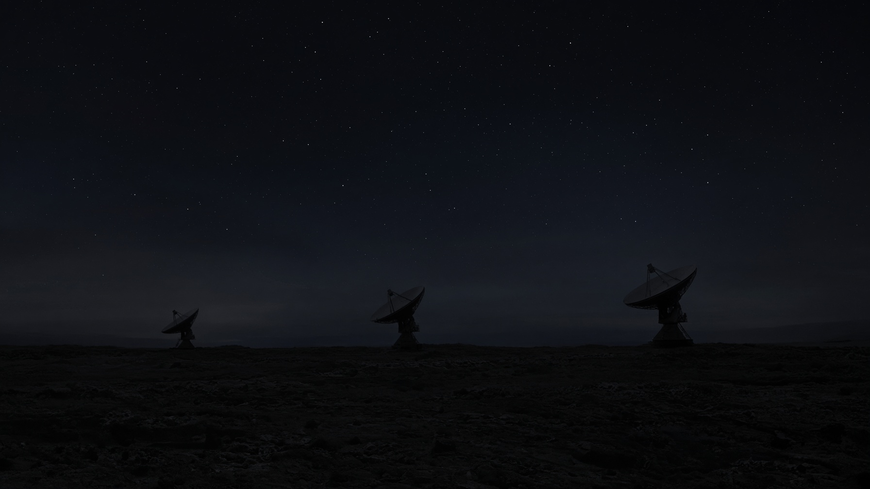 Two distant radio dishes at night. RF as a remote site.
